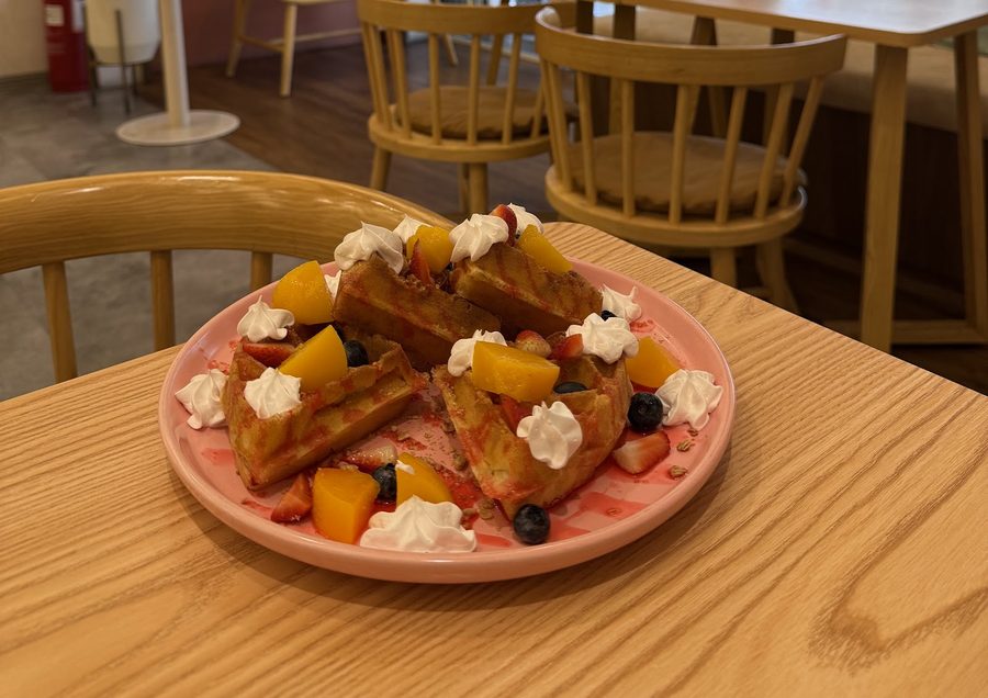 Waffle topped with peaches, blueberries and whipped cream